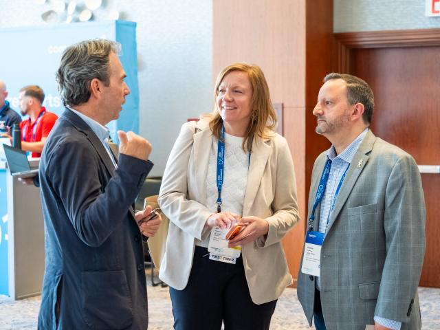 Three attendees talk at the Illuminate 2023 networking reception